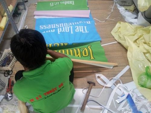 Nhân viên gia công thực hiện nẹp hai đầu của banner rũ in từ silk tại In Kỹ Thuật Số