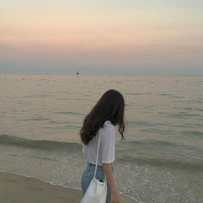 Hình ảnh chụp từ phía sau lưng con gái tóc dài đứng trước biển