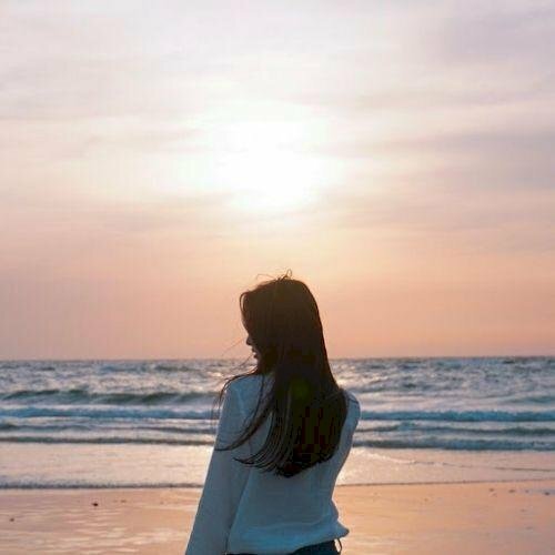 Hình ảnh chụp từ phía sau lưng con gái tóc dài đứng trước biển