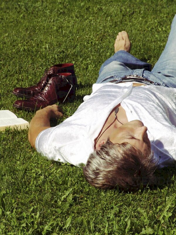 Hình ảnh chàng trai mệt mỏi nằm nhắm mắt trên bãi cỏ