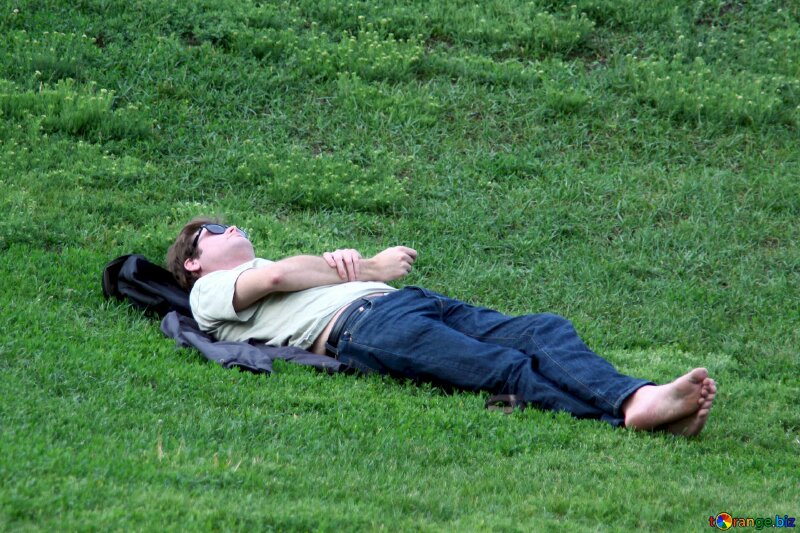 Chàng trai mệt mỏi nằm trên cỏ suy nghĩ về cuộc sống