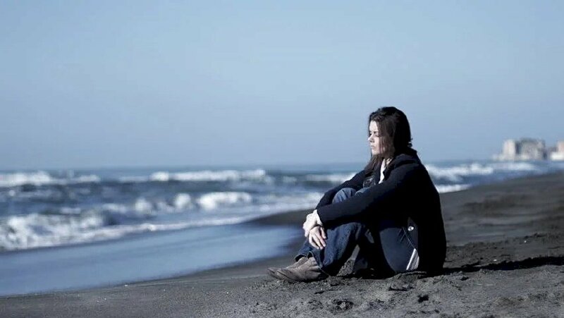 Hình ảnh cô gái ngồi trước biển mang tâm trạng buồn