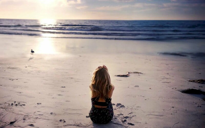 Hình ảnh cô gái một mình ngồi ngắm hoàng hôn trước biển