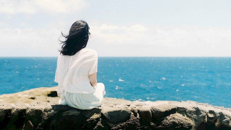 Hình ảnh cô gái đang ngồi ngắm mặt biển xanh bao la