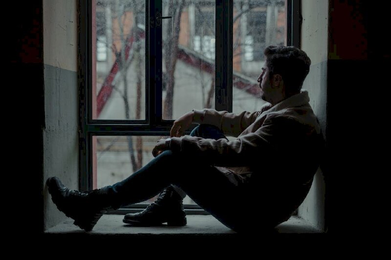 Chàng trai ngồi buồn trầm tư với bao cảm xúc bên khung cửa sổ