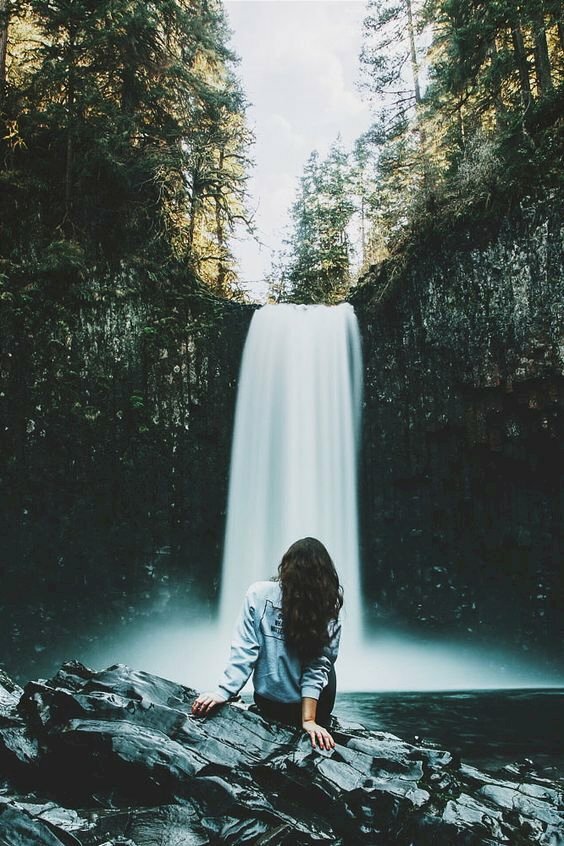 Cách tạo dáng chụp ảnh với thác nước cho nữ với dáng ngồi quay lưng về ống kính, với kiểu này bạn hãy ngồi nhìn vào thác nước, hai tay chống sau lưng, hỏi ngã người ra phía sau.