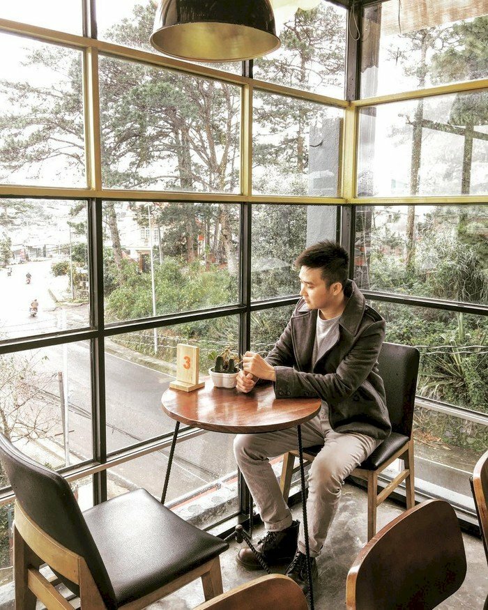 Kiểu tạo dáng nam đặt 2 tay lên bàn, dáng ngồi tự nhiên bên cửa kính đầy cuốn hút