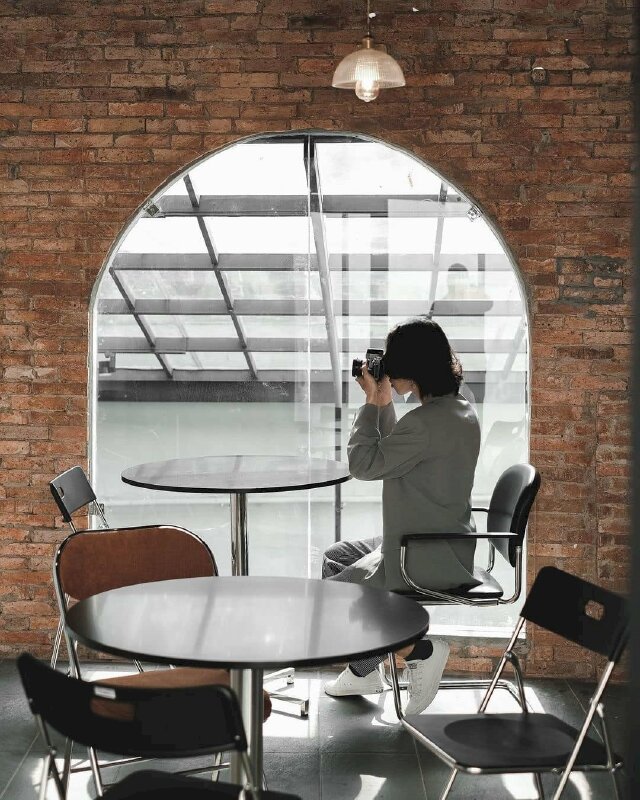 Kiểu tạo dáng thanh niên với bộ tóc dài lãng tử đang ngồi chăm chú với chiếc máy ảnh tạo phong cách nghệ thuật