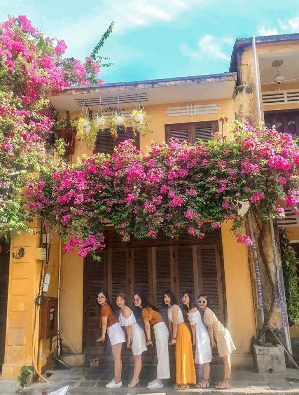 Tạo dáng chụp ảnh Hội An cho nhóm bạn cực chất và hài hước với kiểu đứng xếp hàng người hơi khom, tay tạo dáng phía trước, mắt nhìn ống kính và cười tươi