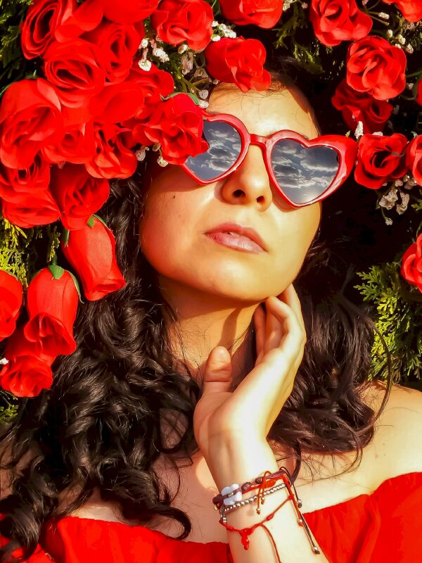 Tạo dáng cô gái trong chiếc kính đỏ 1 tay chạm nhẹ má, mặt hơi ngước tỏa nét sang trọng và quý phái