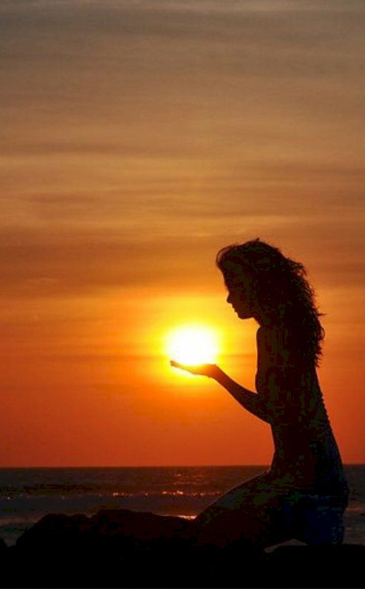 Tạo dáng đẹp, nghệ thuật và chất nhất khi chụp với hoàng hôn mặt trời lặng bên biển với kiểu ngồi khụy gối tự nhiên, 2 tay tạo dáng nâng mặt trời