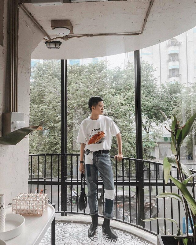 Tạo dáng đứng tự nhiên trong bộ quần áo mang phong cách bụi, nam thần một tay chống lên thành, 1 tay cầm túi, mặt nhìn nghiêng