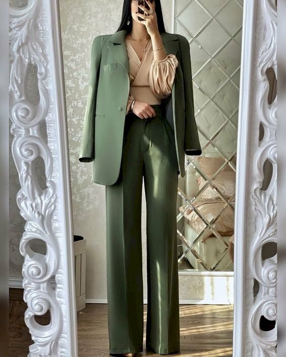 Tạo dáng với vest nữ dài khi chụp trước gương thanh lịch, dịu dàng bằng cách đứng thẳng người, áo vest khoác hững hờ trên vai, 1 tay đặt nhẹ nhàng ngang bụng, còn 1 tay cầm điện thoại chụp hình.