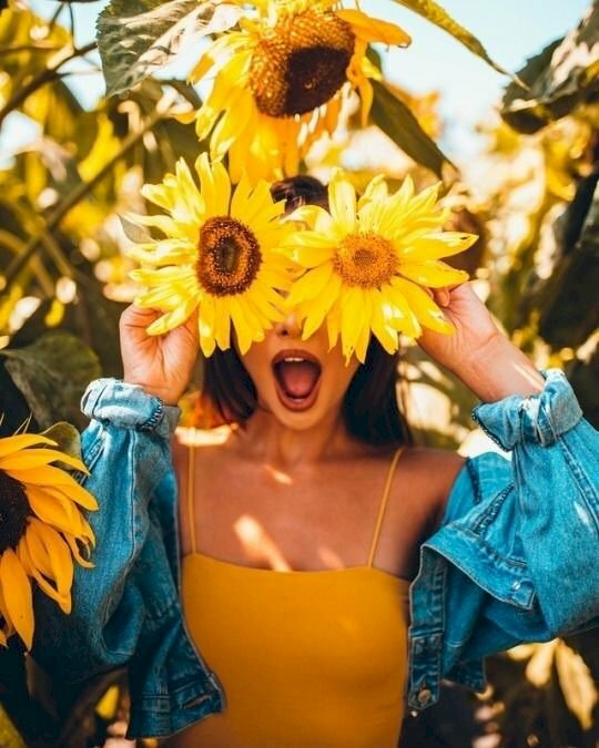 Cách tạo dáng với hoa hướng dương che mặt vô cùng sáng tạo với kiểu, 2 tay cầm 2 bông hoa lên và che hai bên mắt, miệng há để tạo cảm giác vui tươi cho bức ảnh.