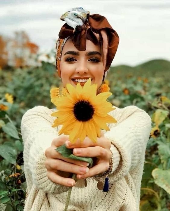 Cách tạo dáng với hoa hướng dương đẹp bằng cánh, hai tay cầm bông hoa hướng dương và đưa thẳng về phía ống kính, chú ý không để bông hoa che mặt, và mặt cười tươi nhìn vào ống kính để có 1 bức ảnh đẹp. 