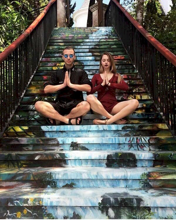 Cách tạo dáng chụp ảnh ở con đường bích họa với những bậc thang là bức vẽ về cảnh sơn thủy hữu tình với dòng suối tươi mát đang chảy, tại đây bạn có thể tạo dáng chụp ảnh sáng tạo với kiểu ngồi chân xếp bằng, hai tay chắp lên giữa ngực, mắt nhắm hờ như đang ngồi thiền. 