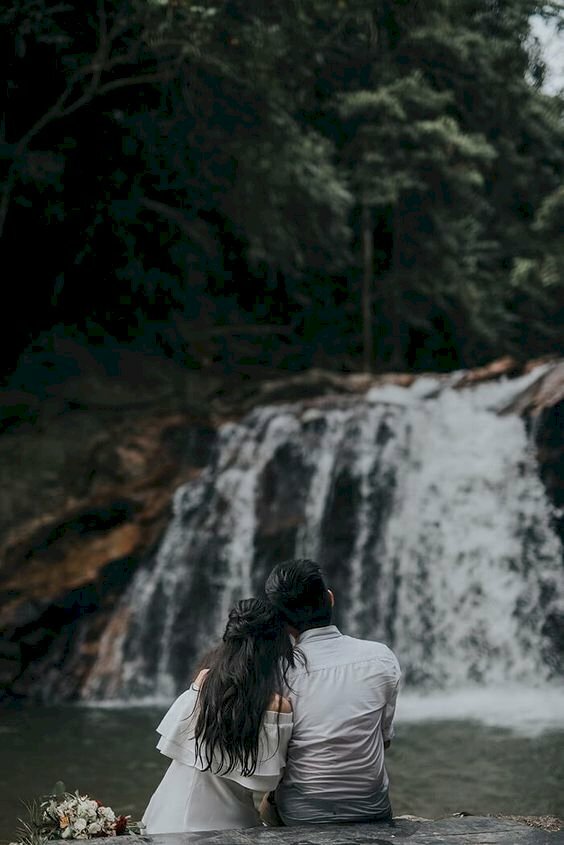 Cách tạo dáng chụp ảnh với thác nước cho cặp đôi đơn giản và tình cảm bằng cách ngồi quay lưng vào ống kính và tựa vào vai nhau.