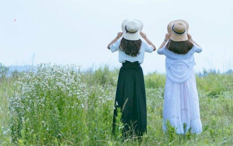 Tạo dáng chụp ảnh đôi bạn thân nữ đứng quay lưng, hai bạn cùng ngước lên nhìn trời, tay cầm nón.