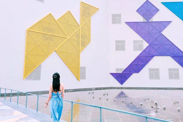 Cách tạo dáng chụp ảnh ở cung văn hóa thiếu nhi dành cho nữ với dáng quay lưng bước đi, vừa nhẹ nhàng vừa nữ tính với gương mặt quay nhìn vào những hình Tangram