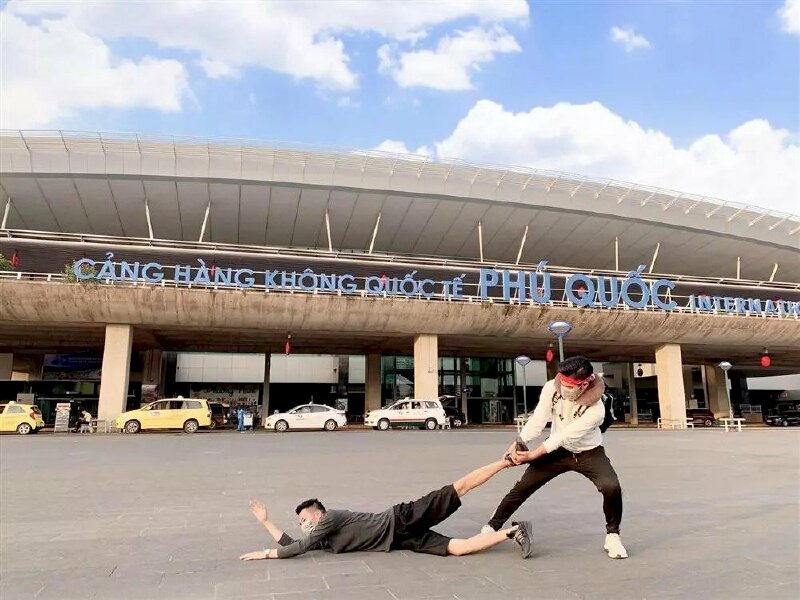 Cách tạo dáng chụp ảnh ở sân bay cho nhóm hai nam cực kỳ hài hước và sáng tạo với một bạn nằm xuống nền và bạn kia thì đang đứng cầm cổ chân bạn kia như kéo đi.