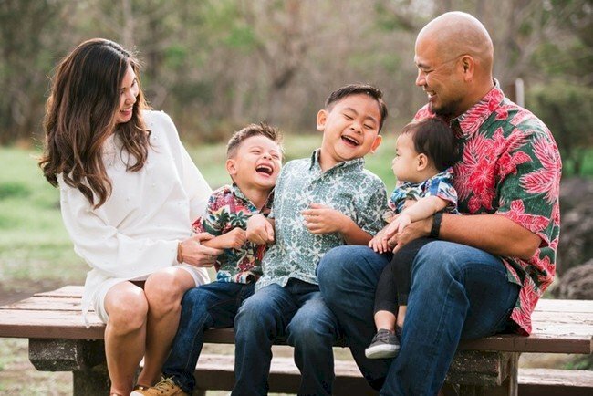 Cách tạo dáng chụp ảnh gia đình 5 người đang ngồi trên ghế vui cười tự nhiên với nhau không nhìn vào ống kính, bố mẹ sẽ ngồi 2 bên ngoài cùng, hai đứa con ngồi giữa và 1 em bé sẽ ngồi vào lòng bố.