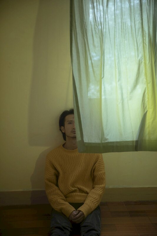 Bạn nam chỉ cần ngồi xuống 1 bên ô cửa, cầm hai tay với nhau, ngồi thẳng lưng tựa vào tường, để rèm cửa tung bay che đi 1 nửa gương mặt là sẽ có một bức ảnh buồn đẹp. 