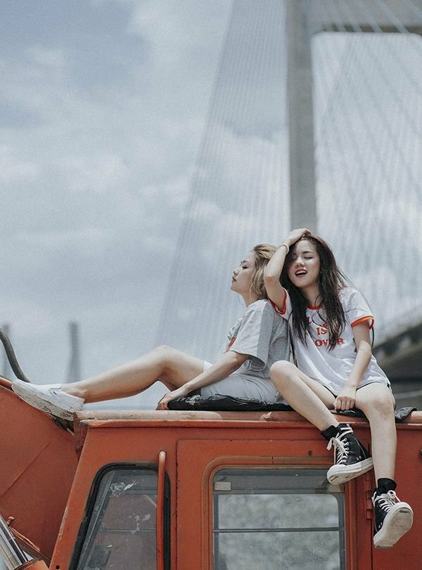 Tạo dáng chụp ảnh đôi nữ cực chất khi ngồi tựa vào nhau, 1 người 1 hướng tạo thành gốc 90 độ, chân để hơi thẳng, 1 bạn đưa tay lên vuốt tóc