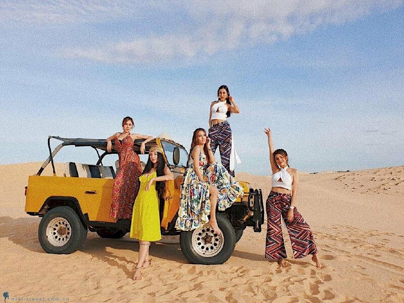 Cách tạo dáng chụp ảnh trên đồi cát cho nhóm bạn thân 5 người cạnh chiếc xe địa hình, với 1 bạn ngồi trên xe, 1 bạn đứng trên nắp capo xe, 1 bạn đứng ở cửa ra vào xe, 1 người đứng tựa vào cửa xe, 1 người đứng trước xe.