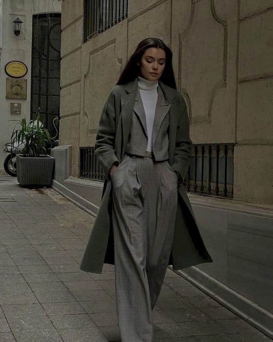 Cách tạo dáng chụp ảnh với vest nữ đang bước đi với hai tay bỏ vào túi quần, dáng chân trước, chân sau đang bước lên, mặt hơi cúi xuống nhìn đường đi.