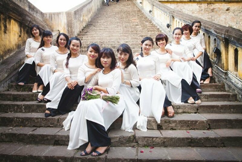 Cách tạo dáng chụp ảnh áo dài tập thể kiểu tập thể đoàn kết với nhóm tầm 15 người, với kiểu này mọi người cùng ngồi trên cầu thang, với 1 người ngồi trước ở giữa, và những người còn lại ngồi tiếp phía sau để tạo thành hình chữ V.