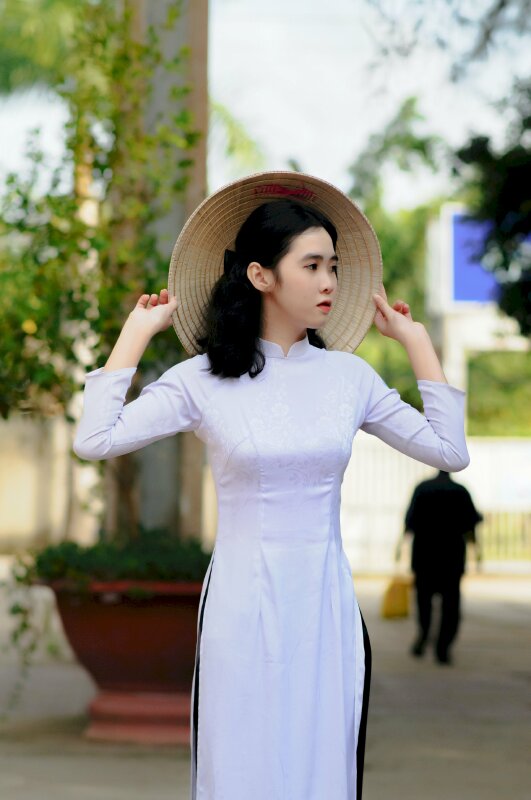 Kiểu tạo dáng đẹp cuốn hút với 2 tay cầm vành nón lá về phía sau gáy, mặt quay ngang, mắt nhìn thẳng