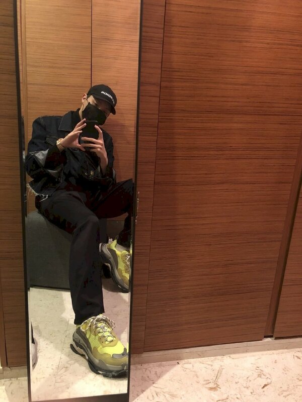 Kiểu tự sướng nam cùng chiếc gương với thời trang màu đen và giày sneaker màu xanh nổi bật phong cách năng động, nam tính cùng dáng ngồi dựa tường thoải mái, 1 chân gác lên ghế, một chân để tự nhiên