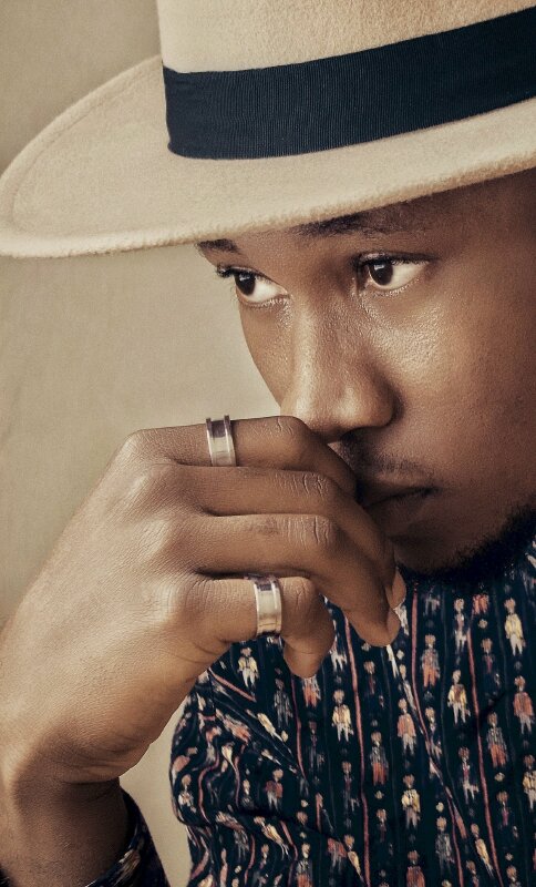 Tạo dáng chụp ảnh cận mặt với chiếc mũ vành mang phong cách quý ông, tay chạm nhẹ mặt, mắt nhìn lên, chụp lấy góc nghiêng