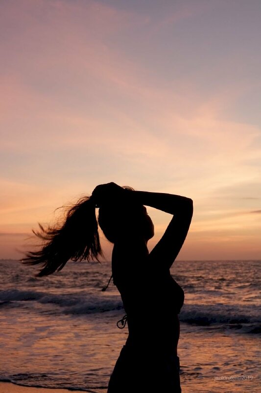 Tạo dáng khi đi biển tuyệt đẹp trong tư thế tay nắm tóc, mặt hơi ngước lên, chụp ở góc nghiêng, đầu hơi ngẩng, mắt nhìn sóng biển