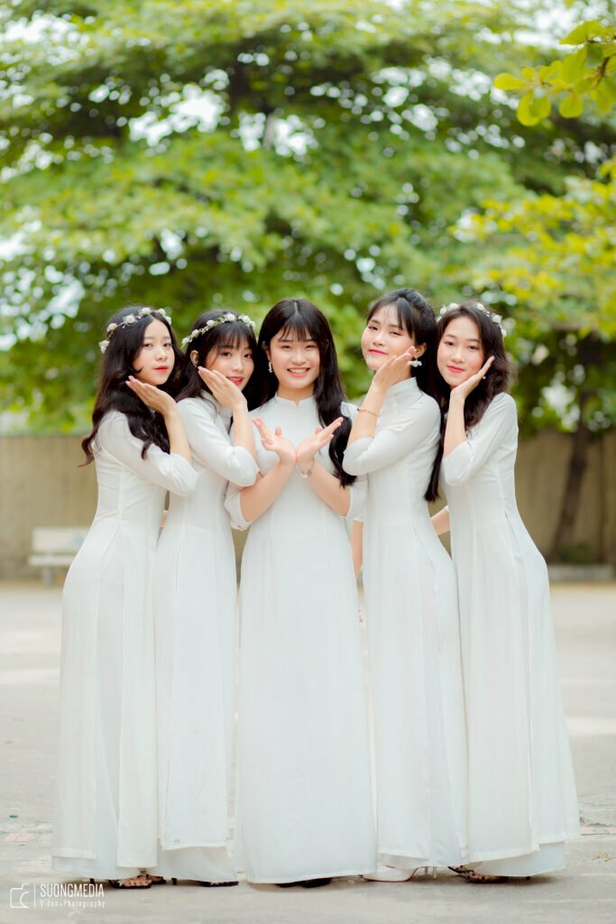 Tạo dáng nữ trong bộ áo dài học sinh cho nhóm 5 bạn nữ vơi nữ chính để 2 tay hình hoa sen, các bạn còn lại đứng hơi nghiêng người, tay chạm nhẹ má