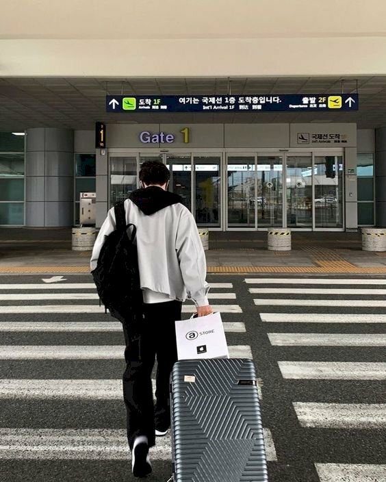 Cách tạo dáng chụp ảnh ở sân bay cho nam với dáng chụp sau lưng, đang bước đi và một tay kéo vali trên đường.