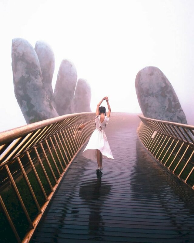Tạo dáng của cô gái trên chiếc Cầu Vàng Đà Nẵng trong chiếc váy trắng xòe cùng tư thế đưa 2 tay lên cao, chân nhón gót tạo hình ảnh như đang nhảy múa yêu đời