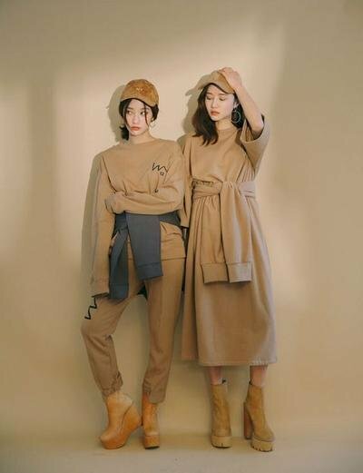 Cách tạo dáng chụp ảnh đôi nữ cực chất đậm chất vintage trong trang phục màu be, với dáng đứng thẳng hơi tựa lưng vào tường, đưa chân lên tạo hình chữ D.