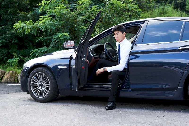 Cách tạo dáng chụp ảnh nam ngồi trên xe hơi với 1 chân bỏ xuống đường, 1 chân còn đặt trên xe, 1 tay chống lên chân chân bỏ xuống tạo sự ngầu, sang trọng cho nam khi chụp ảnh với xe hơi.