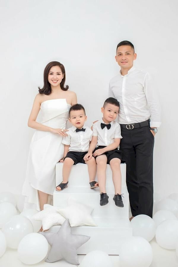 Cách tạo dáng chụp ảnh gia đình kiểu Hàn Quốc với kiểu tạo dáng bố mẹ đứng và hai con ngồi trên ghế ở giữa, cả nhà cười tươi cùng nhìn vào ống kính máy ảnh. 