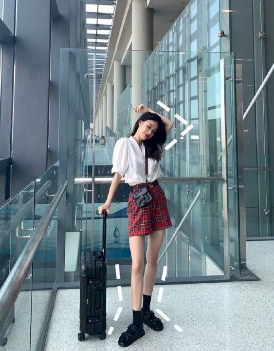 Cách tạo dáng chụp ảnh đứng ngầu cho nữ khi đứng với vali, đầu hơi nghiêng, tay để vòng nhẹ qua đầu