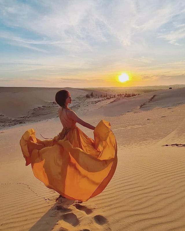 Cách tạo dáng chụp ảnh trên đồi cát cho nữ tuyệt đẹp dành cho cô nàng mặc váy maxi dài, hãy đứng tung váy để váy tung bay trước gió, thân hình cô gái như đang múa, kết hợp với ánh hoàng hôn buổi chiều sẽ giúp bạn có tấm ảnh tuyệt đẹp trên đồi cát.