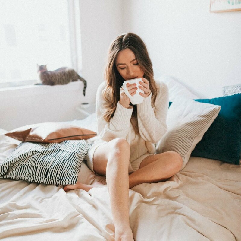 Tạo dáng ngồi thưởng thức cafe trên giường của cô gái tr3 với tư thế ngồi tự nhiên, một chân co gối, 2 tay nâng cốc cafe đưa lên miệng, đầu hơi cúi, mắt nhắm nhẹ tạo nét thưởng thức rất chill