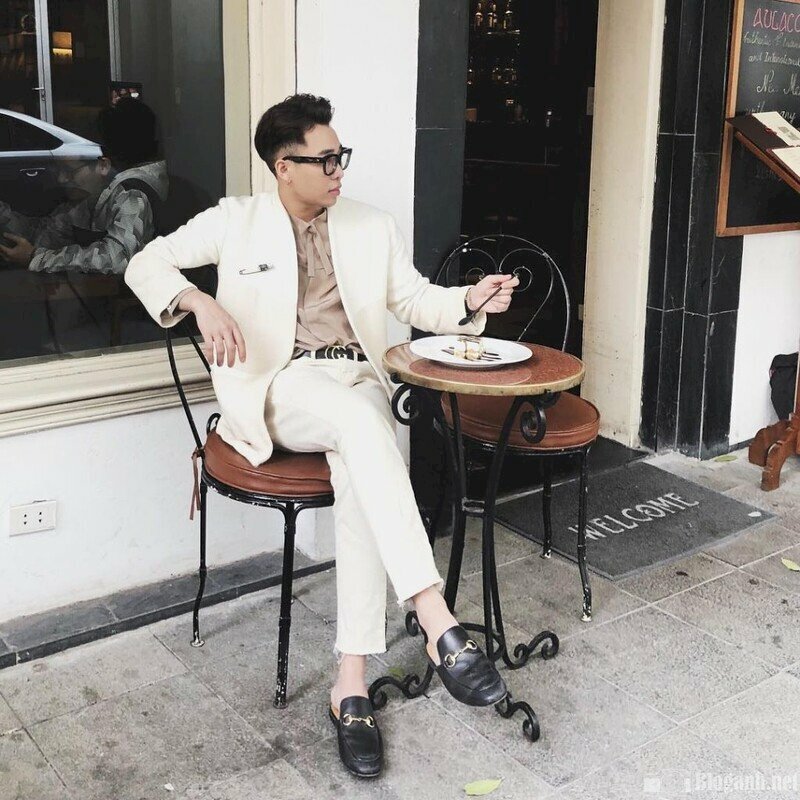 Cách tạo dáng thần thái sang trọng trong bộ đồ vest lịch lãm màu trắng một tay chống lên ghế, một tay cầm thìa, ngồi bắt chéo chân