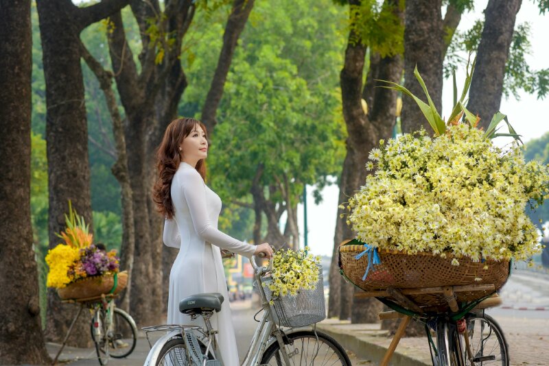 Kiểu tạo dáng đứng nữ cùng chiếc xe đạp giỏ chứa hoa chụp lấy dáng nghiêng người, đầu hơi ngẩng, mắt nhìn lên phía xa