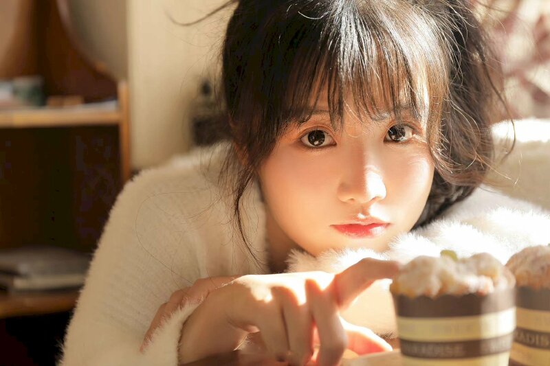 Kiểu tạo dáng nữ dễ thương với tư thế ngồi tựa càm lên tay đặt trên bàn, một tay ngón chạm nhẹ vào miệng ly, 2 mắt to nhìn thẳng camera