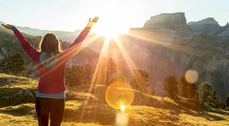 Tạo dáng chụp ảnh đón chào bình minh của cô gái mặc chiếc áo ấm màu đỏ trong tư thế đưa 2 tay lên cao đón ngày mới nắng vàng rực rỡ