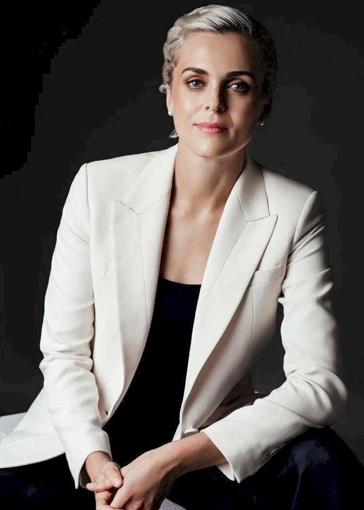 Tạo dáng chụp ảnh cho nữ doanh nhân nổi bật với chiếc áo khoác ngoài màu trắng, nét diện miệng cười nhẹ, mắt nhìn thẳng ống kính