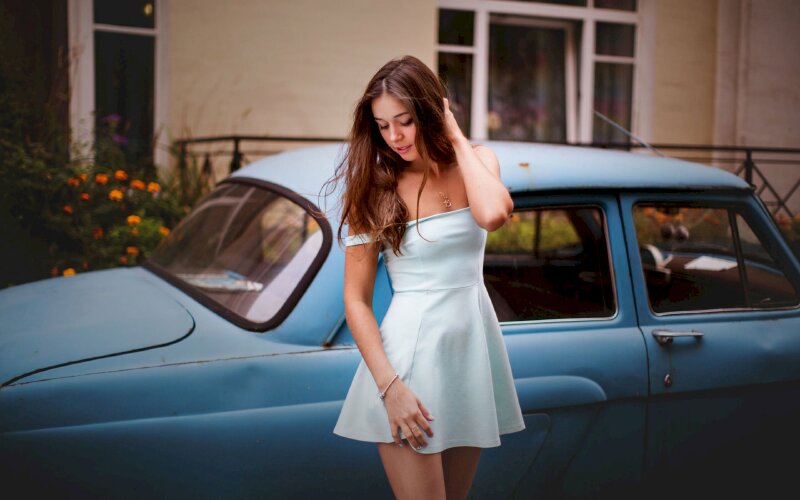 Kiểu tạo dáng của cô gái chụp ảnh cùng chiếc ô tô đời cũ trong bộ váy xanh nhạt, dáng đứng thẳng, đầu hơi nghiêng, một tay chạm đùi, tay chạm tóc, mắt nhìn xuống đất tuyệt đẹp