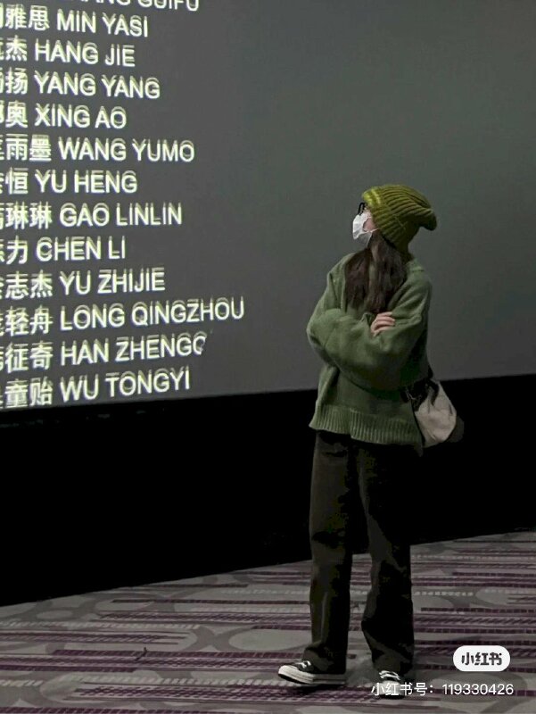 Tạo dáng cùng màn hình chiếu phim trong rạp trong phong cách thời trang thoải mái và chiếc nón lên cá tính của cô gái đứng khoanh tay, mặt quay nhìn màn hình